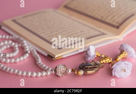 Heiliger Koran mit Rosenkranz Perlen mit rosa Hintergrund Stockfoto