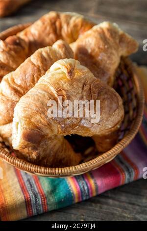 Warme Croissants, in einem Korb mit einem gestreiften Serviette serviert serviert, über alten Holztisch. Retro Stil Verarbeitung und Vignette Stockfoto