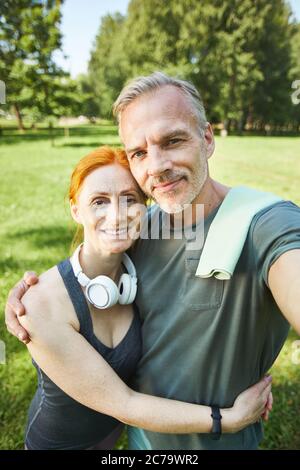 Selbstporträt von glücklich sportlich reifen Paar umarmen einander in schönen Park Stockfoto