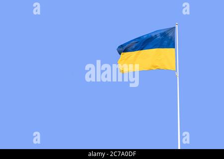 Ukrainische Flagge, die auf einem Fahnenmast gegen den blauen Himmel fliegt. Die Flagge der Ukraine winkt im Wind Stockfoto