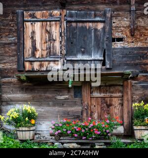 Alte Schweizer Holzhütte mit Pelargonium Blumen geschmückt Stockfoto