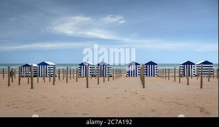 Reihe von blau und weiß gestreiften Strandhütten gegen blauen Himmel Stockfoto