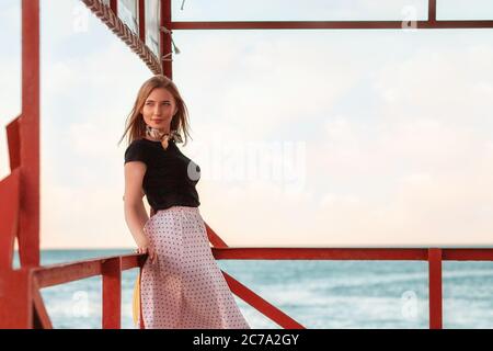 Sommerurlaub. Porträt einer schönen Dame in einem Kleid posiert auf dem Pier am Meer. Abend. Speicherplatz kopieren. Stockfoto