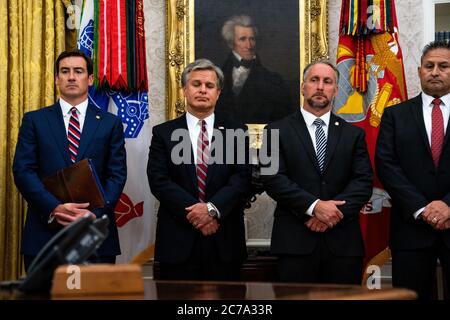 Von links nach rechts: Zachary Terwilliger, Rechtsanwalt der Vereinigten Staaten, Eastern District of Virginia, Direktor Christopher Wray, Federal Bureau of Investigation, Matthew Albence, kommissarischer Direktor, Immigration and Customs Enforcement, Department of Homeland Security, rechts, Und Michael Carvajal, Direktor des Federal Bureau of Prisons, schauen auf, wie Präsident Donald Trump Reporter im Oval Office des Weißen Hauses nach einer Unterweisung von der Strafverfolgung über “Keeping American Communities Safe: Die Takedown der Schlüssel MS-13 Criminal Leaders" in Washington DC, am 15. Juli 2020.Quelle: An Stockfoto