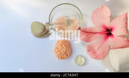 Spa-Ambiente und Spa-Hintergrund Komposition mit Hibiskusrosa Blume auf weißem Hintergrund. Banner. Speicherplatz kopieren. Handtuch, Kerzen, Blumen, Steine . Massa Stockfoto