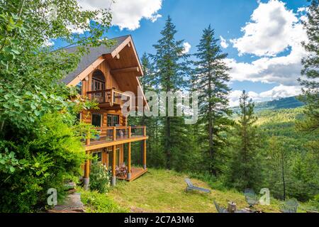 Ein gehobenes ländliches Blockhaus auf einem Hügel in den Bergen in der Nähe von Sandpoint, Idaho, USA, während des Sommers. Stockfoto