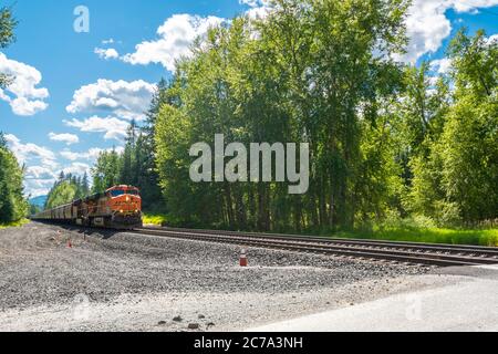 Eine Lokomotive, die sich auf den Gleisen bewegt, fährt in Richtung einer Kreuzung in einer Bergstadt in Nord-Idaho, USA Stockfoto
