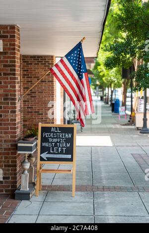 Amerikanische Flagge hängt an einem Schaufenster in einer kleinen Stadt. Das Schwarze Brett liefert Konzepte für politische Positionen. Stockfoto