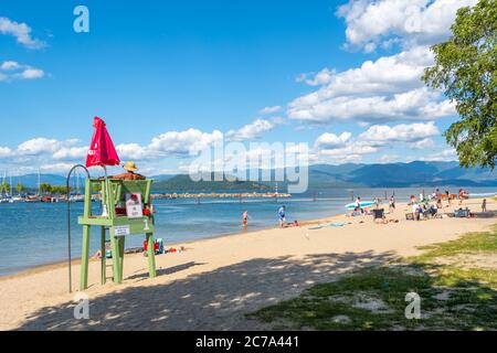 Ein männlicher Rettungsschwimmer sitzt im Sommer in einer Rettungswache am sandigen Sandpoint City Beach am Lake Pend Oreille im Nordwesten der USA. Stockfoto