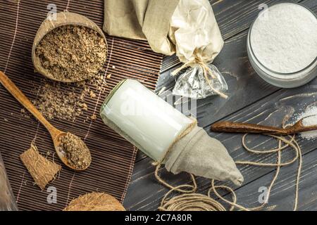 Kokosöl mit frischer Nuss auf altem Holztisch. Kokosöl und Kokosnüsse. Bio-Kokosnussprodukte für Spa. Stockfoto