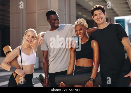 Multiethnische Gruppe von Menschen, die nach dem Training im Freien zusammen stehen. Männer und Frauen in Sportbekleidung stehen zusammen und schauen auf Kamera und Stockfoto