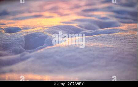 Natürlicher Winterhintergrund mit Schneeverwehungen bei Sonnenuntergang. Geringe Schärfentiefe Stockfoto