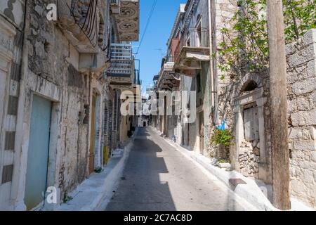 Eine schmale Gasse zwischen Steinhäusern mit traditionellen geometrischen Mustern an den Fassaden und Balkonen. Stockfoto