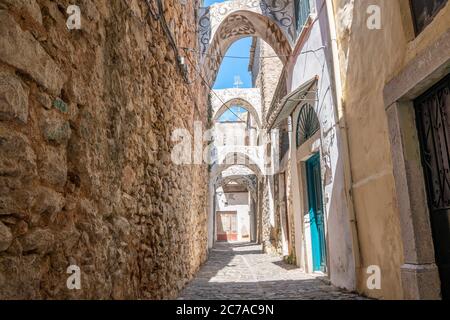 Eine schmale Gasse zwischen Steinhäusern mit traditionellen geometrischen Mustern an den Fassaden und Balkonen. Stockfoto