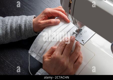 Gesichtsmaske Nähen zu Hause gegen Coronavirus. Stockfoto