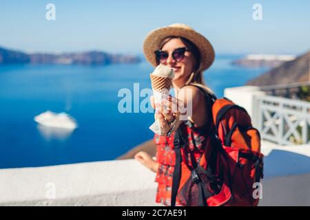 Frau, die auf der Insel Fira Santorini im Hintergrund des Caldera-Meeres Eis isst. Essen im Sommer. Stockfoto