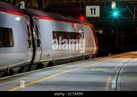 Virgin Trains Alstom Pendolino Zug am bahnhof crewe auf der Hauptlinie der Westküste mit einem grünen und roten Eisenbahnsignal Stockfoto