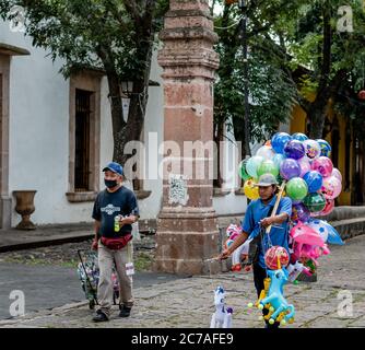 Zwei hispanische Männer tragen Masken, die Spielzeug in den Straßen von Morelia Mexiko verkaufen Stockfoto