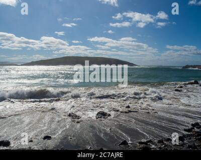 Muttonbird Island auf der anderen Seite des Hafens, sanfte Wellen, die Muster bilden, während das Wasser über den Strand spült Stockfoto