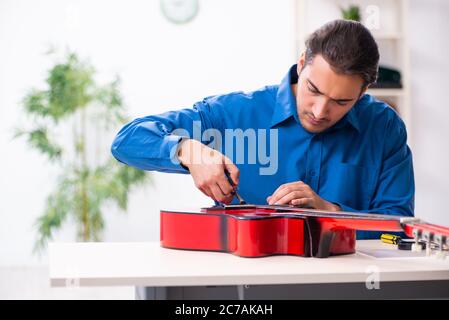 Junger Mann Reparatur der Gitarre Stockfoto