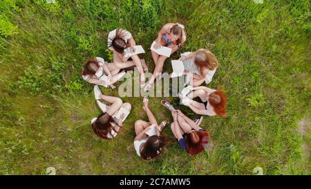 Teamwork-Konzept. Eine Gruppe Studentinnen sitzt auf dem Gras und löst Probleme. Stockfoto
