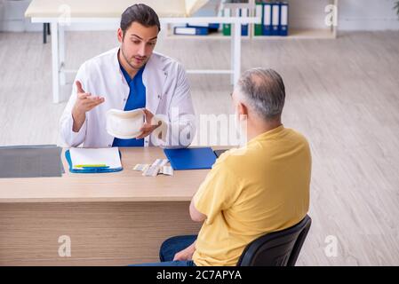 Alter Hals verletzten Mann besucht jungen Arzt Stockfoto