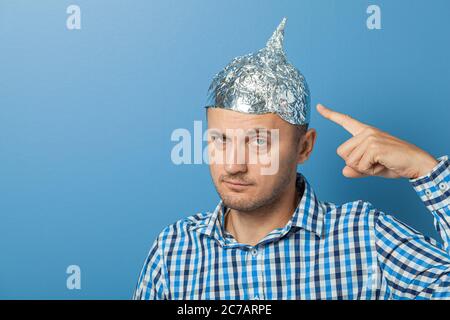 Mann mit ernster Gesichts zeigt einen Finger an einer Kappe mit Aluminiumfolie. Schützt vor dem Lesen denken. Stockfoto