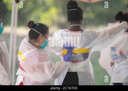 Austin, TX USA 15. Juli 2020:Medizinische Techniker, die für Austin Public Health arbeiten, ziehen Schutzkleidung (PSA) an und führen kostenlose COVID-19-Vorführungen in einem öffentlichen Park durch. Texas hat einen enormen Anstieg bei Coronavirus-Fällen mit fast 300,000 Fällen gesehen, die zu mindestens 3,432 Todesfällen geführt haben. Kredit: Bob Daemmrich/Alamy Live Nachrichten Stockfoto