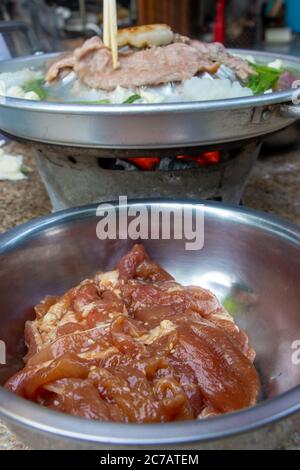 Ein rohes Schweinefleisch in einer Schüssel bereit zum Grillen bei Thai Barbecue Stil. Eine Zubereitung von gebratenem Fleisch mit Gemüsesauce auf Hot Pot - Mu Kratha, close up Stockfoto