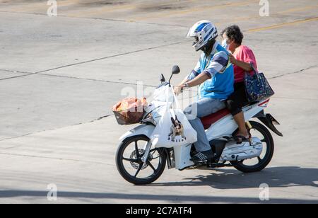 SAMUT PRAKAN, THAILAND, JULI 01 2020, EIN Taxifahrer auf einem Motorrad fährt mit einer Frau und ihren Einkaufstaschen. Der mototaxi Fahrer trägt einen Beifahrer Stockfoto