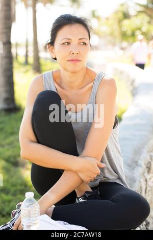 Portait einer fitting Frau, die draußen am Strand sitzt. Stockfoto