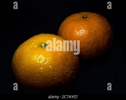 Nahaufnahme des Wassertropfens auf glänzender Oberfläche von Frische Orange auf schwarzem Hintergrund Stockfoto