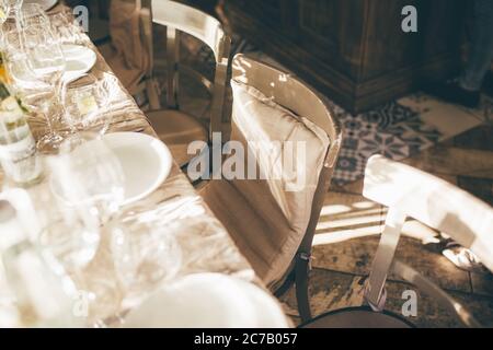 Hochzeit. Bankett. Die Stühle und der Tisch für die Gäste, mit Kerzen dekoriert, mit Besteck und Geschirr serviert und mit einer Tischdecke bedeckt. Der Tabelle Stockfoto