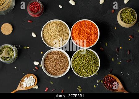 Draufsicht auf Keramikschalen mit verschiedenen Körnern auf Holztisch Stockfoto