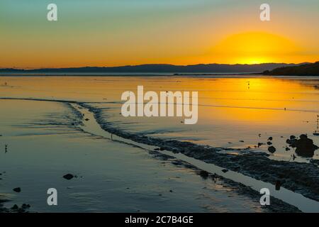 Ebbe-Watt mit kleinem Bach bei Sonnenaufgang auf der Halbinsel Coromandel Neuseeland. Stockfoto