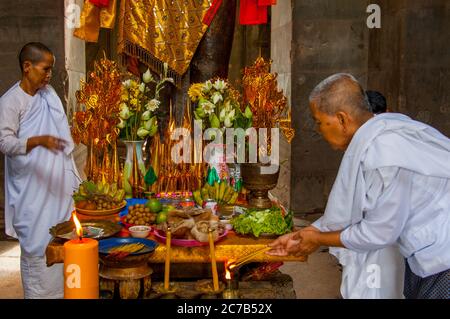 Eine buddhistische Nonne ordnet Opfergaben an der Basis einer dekorierten Statue von Herrn Vishnu, einem Hindu-gott, dem Obersten Gott des Vaishnavismus (einer der drei Stockfoto