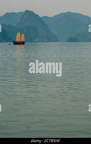 Ein Touristenschrott (Boot), der zwischen den Kalksteinfelsen-Inseln der Halong Bay (UNESCO-Weltkulturerbe) in der Nähe von Haiphong in Nordvietnam fährt. Stockfoto