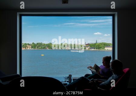 Menschen genießen den Blick auf den Mälarsee, lesen und trinken Kaffee. Blick auf die großen Panoramafenster im Café auf der Oberseite der Fotografiska Stockfoto