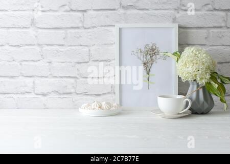 Grüne Hortensien in einer grauen Vase im nordischen Stil stehen auf einem weißen Holztisch. Background alten Ziegel. Paket, Kopierbereich. Stockfoto