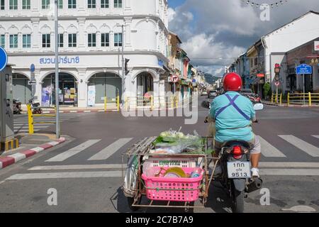 Ein Motorradfahrer mit Seitenwagen hält an der Ecke Phuket Rd. / Thalang Rd. In Phuket Town, Phuket, Thailand, vor einem großen weißen Gebäude Stockfoto