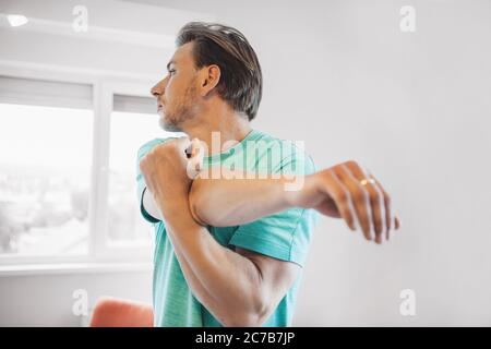 Nahaufnahme eines kaukasischen Mannes mit blondem Haar und Borsten, der sich aufwärmt, bevor er zu Hause Yoga macht Stockfoto