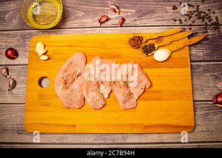 Fleischsteaks und verschiedene Gewürze auf einem Holzbrett. Nahaufnahme Stockfoto