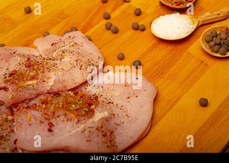 Fleischsteaks und verschiedene Gewürze auf einem Holzbrett. Nahaufnahme Stockfoto