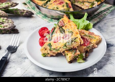 Portion Frittata. Aus Eiern, Spargel und Kirschtomaten. Italienische Küche Stockfoto