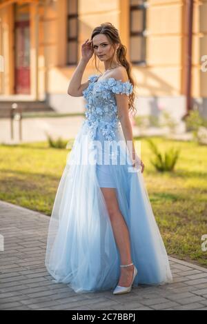 Russische Absolventen posieren in einem schönen Kleid vor dem Hintergrund ihrer Schule. Stockfoto