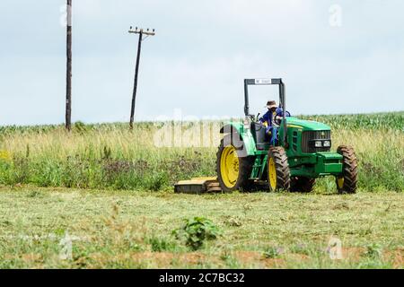 Afrikanischer Bauer, Arbeiter, Arbeiter sitzt in einem Traktor und räumt das Land um sein Feld in Kwazulu Natal, Südafrika Stockfoto