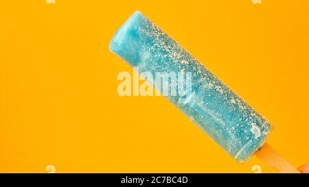Helles Fruchteis auf einem Stock auf gelbem Hintergrund. Gefrorenes Fruchteis. Sommerstimmung. Kühlendes Dessert bei heißem Wetter. Lieblingsessen für Stockfoto