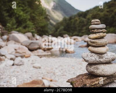 Nahaufnahme eines sorgfältig gebauten Felsenkairns am ruhigen Flussufer eines Alpenflusses in der Schweiz. Stockfoto