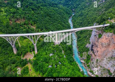 Durdevica Brücke über den schönen smaragdgrünen Fluss Tara im Norden Montenegros. Seitenansicht von oben von fliegender Drohne Stockfoto