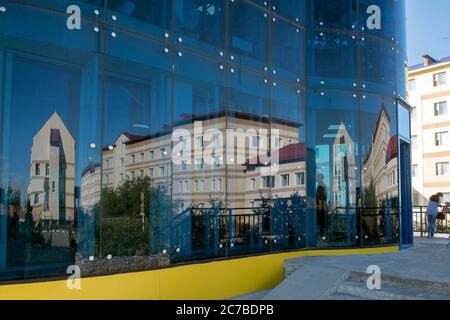 Verzerrte Spiegelung der Stadt in Glaswand Stockfoto